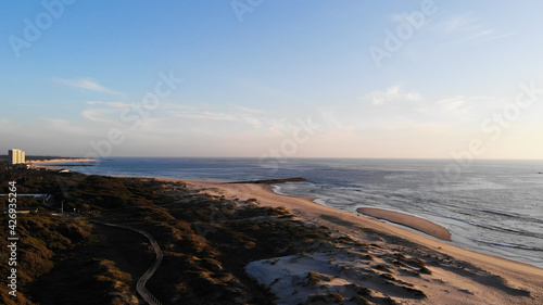 Aerial view of the Northern Litoral Natural Park in Ofir, Esposende, Portugal. Wooden boardwalk and the Ofir Towers in the background. Sea, beach boulders, pebble shore and waves at sunset. photo