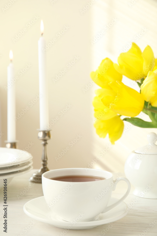 Tea set, candles and flowers on white wooden table