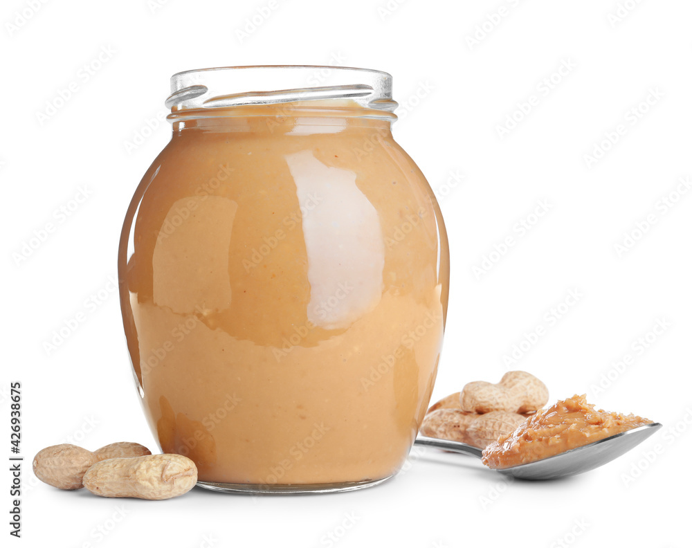 Glass jar and spoon with tasty peanut butter on white background Glass jar and spoon with tasty peanut butter on white background