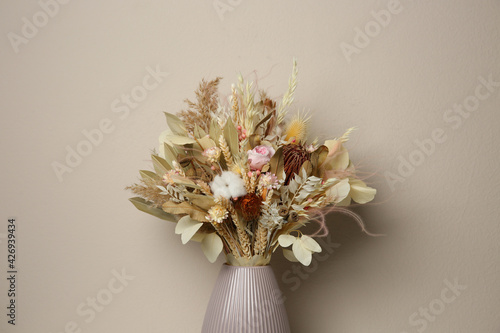 Beautiful dried flower bouquet in ceramic vase against light grey background