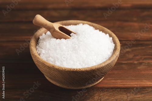Bowl with natural sea salt and scoop on wooden table
