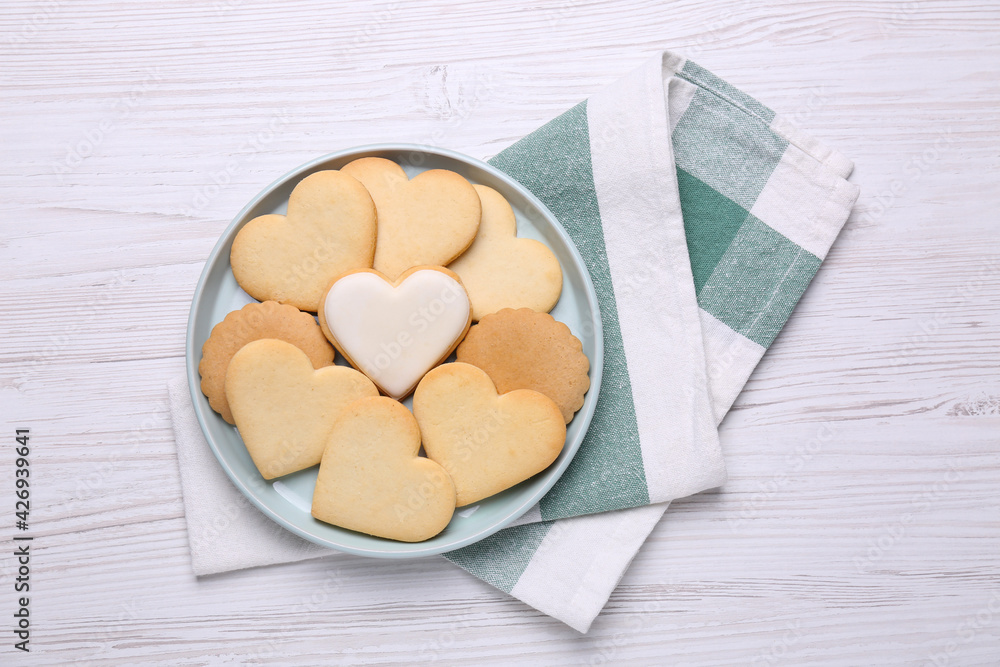 Obraz premium Heart shaped cookies and napkin on white wooden table, flat lay