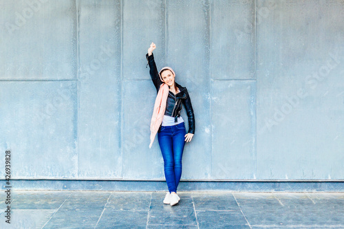 Canvas-taulu Happy woman leaning against a wall with pink scarf on her head in symbol beating