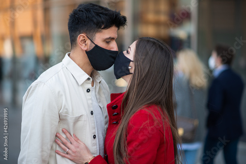 Couple kissing while wearing a covid or coronavirus mask