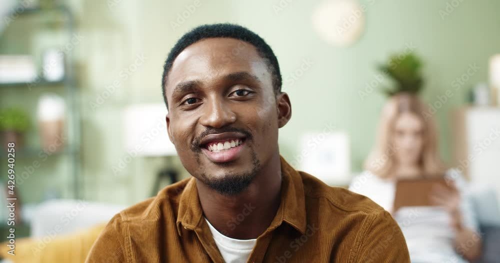 Close up portrait of happy african american young man at home, turning head looking at camera smiling. Close up portrait of happy african american young man at home, turning head looking at camera smiling.