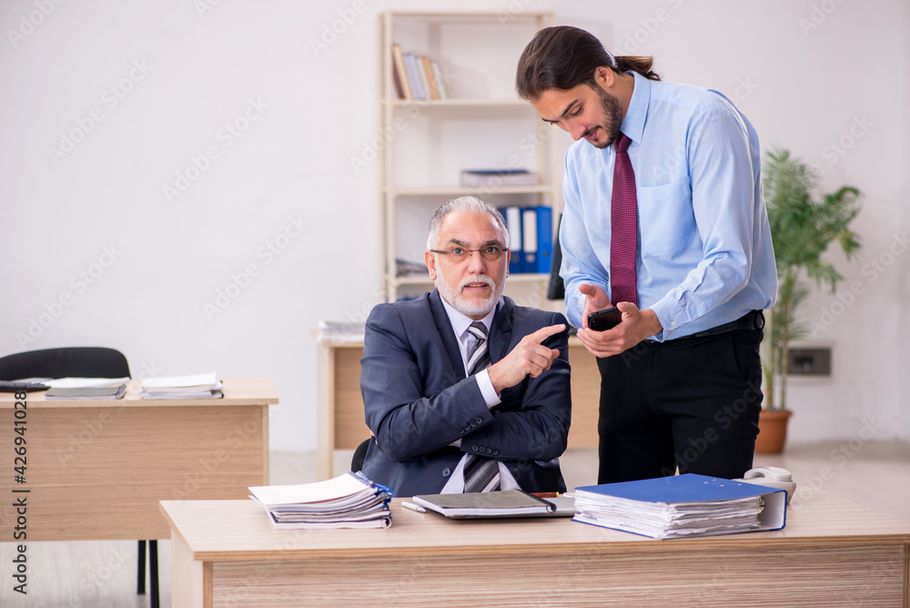 Old male boss and young employee working in the office Old male boss and young employee working in the office