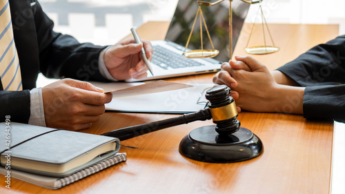 Fotografie The judge hammer and the scales of a fair uncle on a table where a lawyer advises clients