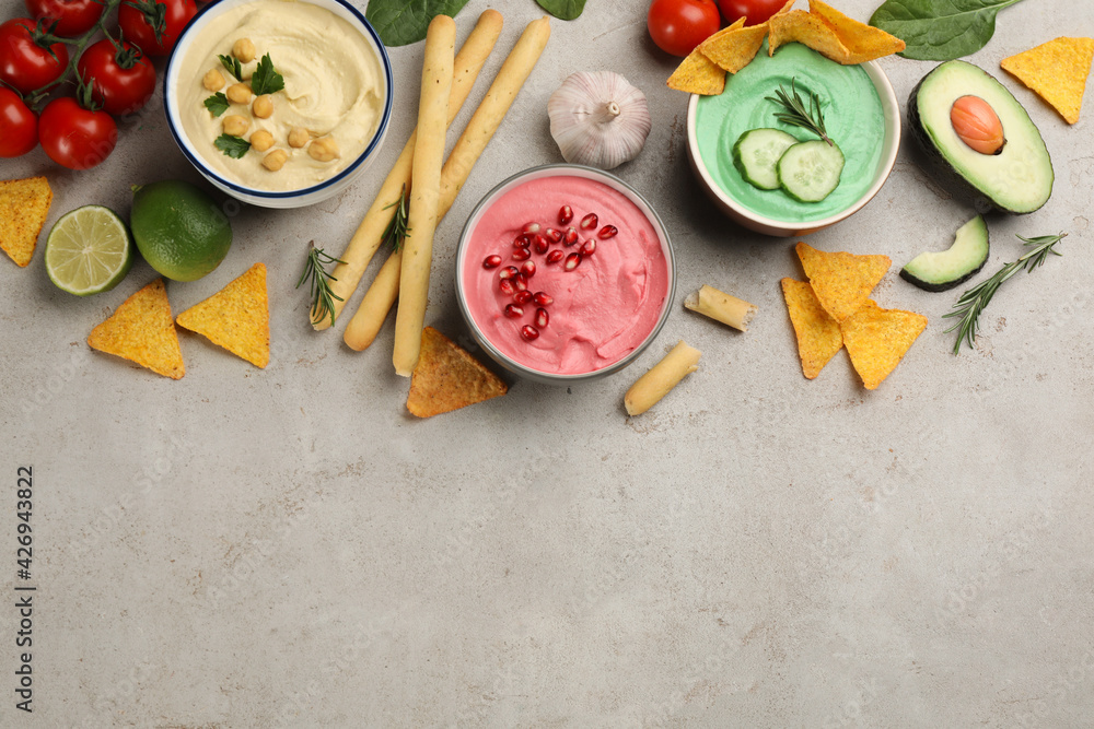 Different kinds of tasty hummus and snacks on light table, flat lay. Space for text Different kinds of tasty hummus and snacks on light table, flat lay. Space for text