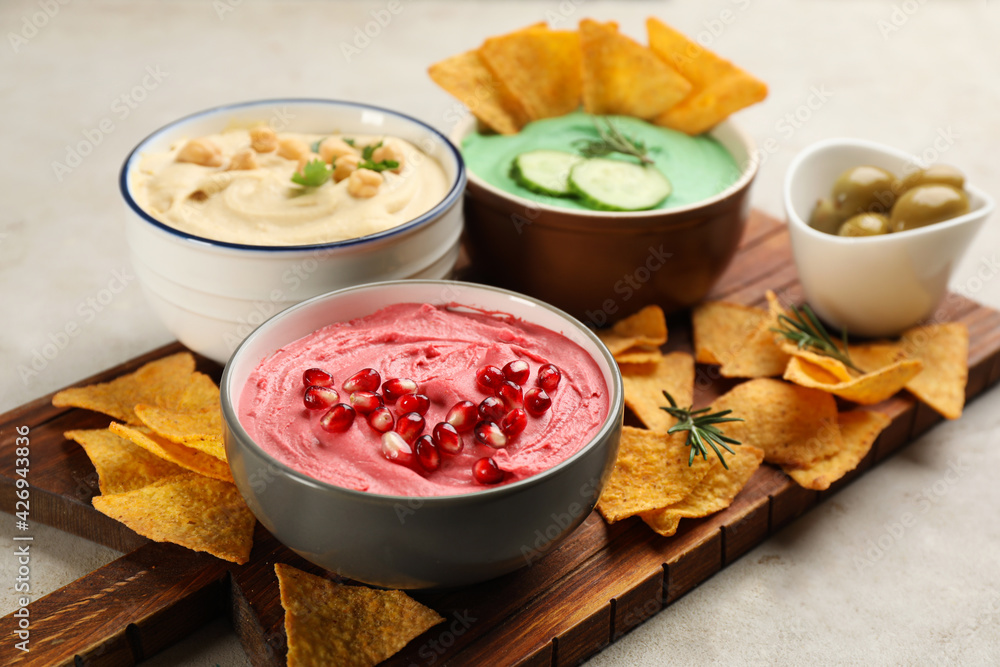 Different kinds of tasty hummus served with nachos on light table Different kinds of tasty hummus served with nachos on light table