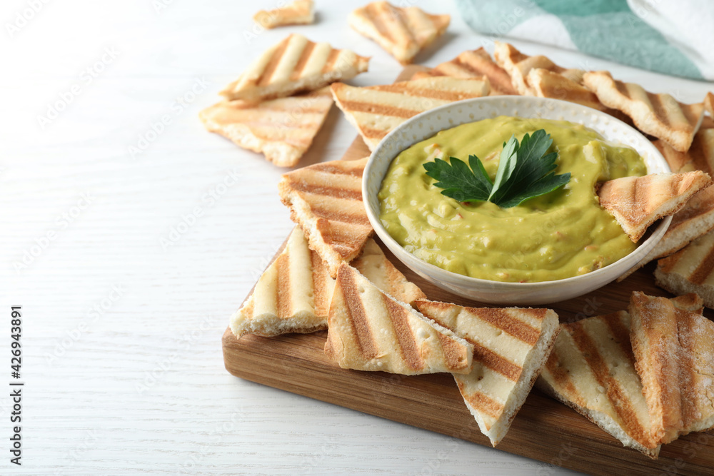 Delicious pita chips and hummus on white wooden table, closeup Delicious pita chips and hummus on white wooden table, closeup