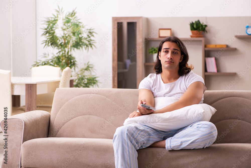 Young lazy man in oversleeping concept at home Young lazy man in oversleeping concept at home