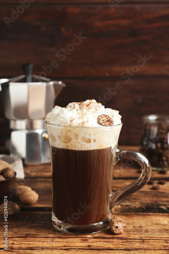 Coffee drink with nutmegs and whipped cream on wooden table