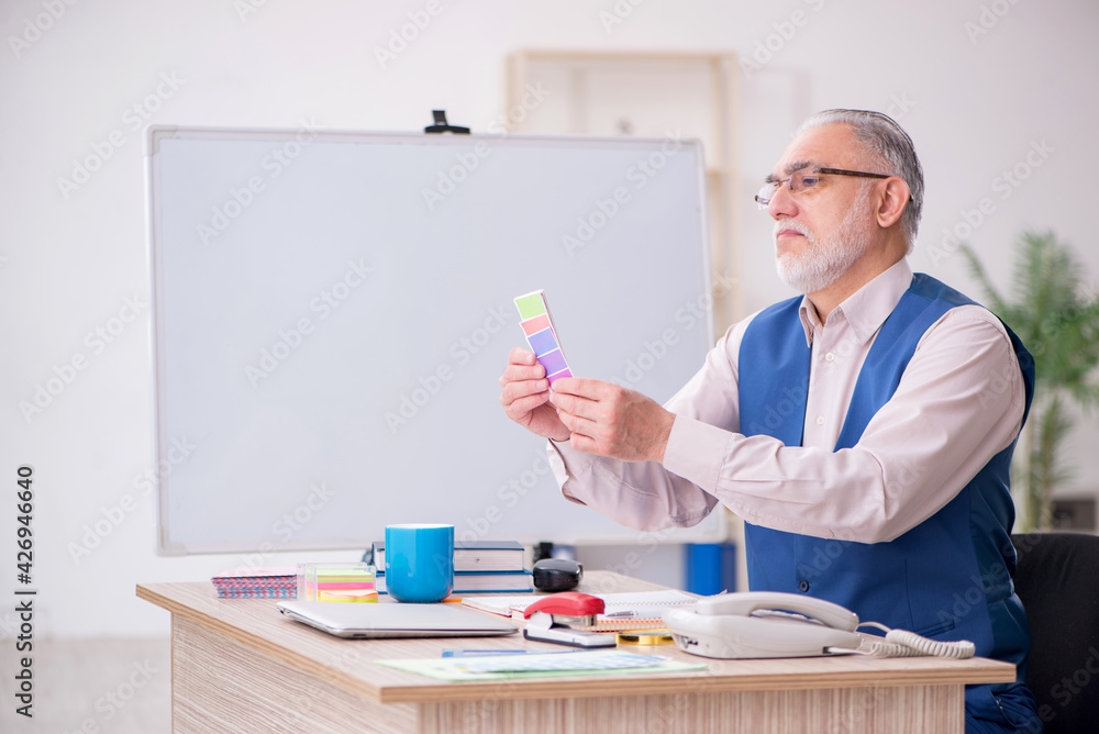 Old male designer working in the office Old male designer working in the office