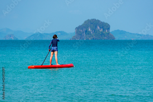 young sporty woman playing stand-up paddle board on the blue sea in sunny day of summer vacation © plo