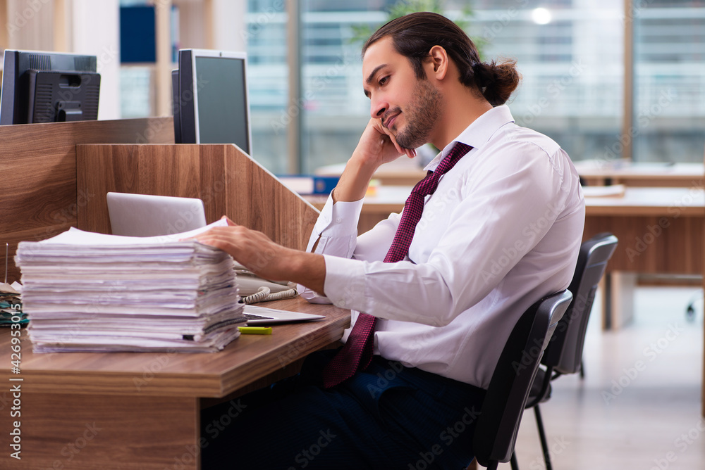 Young male employee and too many work in the office Young male employee and too many work in the office