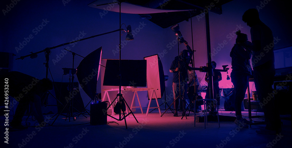 Neon Blue pink color shooting. behind the scene of video production set up in the big studio. Crew team working and camera equipment in silhouette. Movie production industry. Lighting set up. - obrazy, fototapety, plakaty 