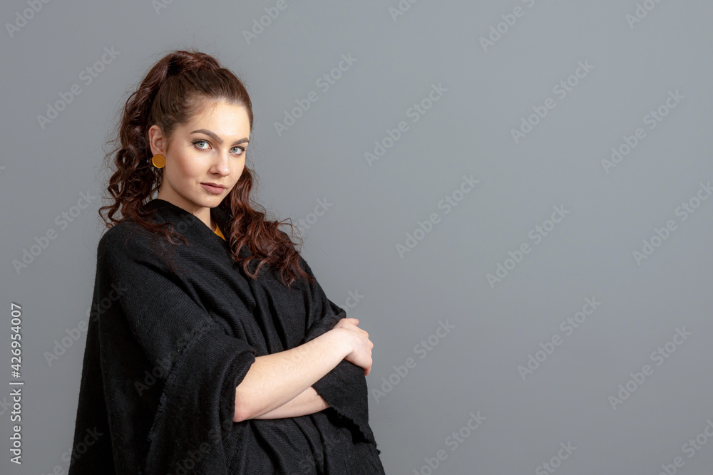portrait of charming curly-haired woman in a black cloak isolated on a gray background portrait of charming curly-haired woman in a black cloak isolated on a gray background