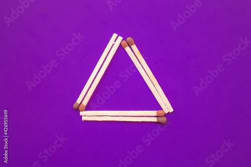 triangle of luminates on a purple background from matches. symbol of the masons, satanists