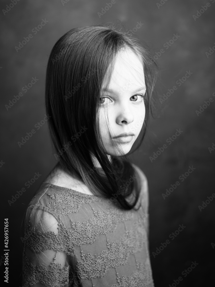 Portrait of a little girl in a dress on a dark gray background photograph cropped side view Portrait of a little girl in a dress on a dark gray background photograph cropped side view