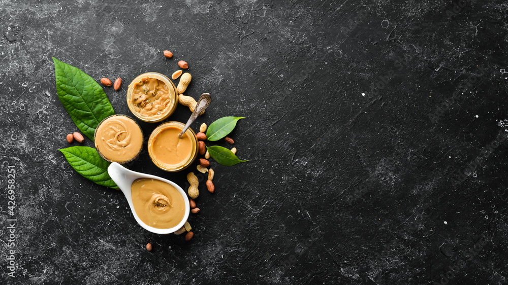 Peanut butter and nuts on a black stone background. Healthy food. Top view.