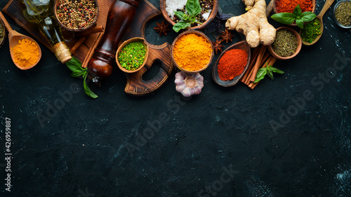 Colorful herbs and spices for cooking. Indian spices. On a black stone background. Top view.