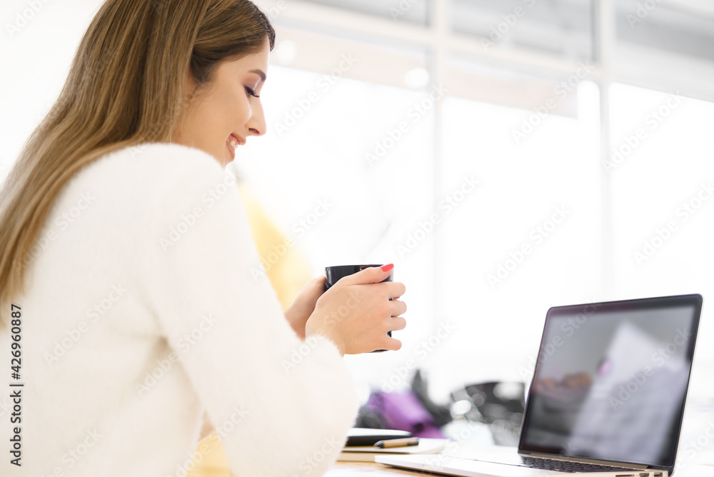 Beautiful Caucasian woman thinking about something while sitting with notebook in a minimal cafe bar. Charming female freelancer thinking about new ideas during work on laptop drinking coffee Beautiful Caucasian woman thinking about something while sitting with notebook in a minimal cafe bar. Charming female freelancer thinking about new ideas during work on laptop drinking coffee