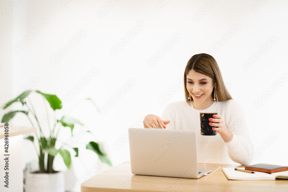 Beautiful Caucasian woman thinking about something while sitting with notebook in a minimal cafe bar. Charming female freelancer thinking about new ideas during work on laptop drinking coffee Beautiful Caucasian woman thinking about something while sitting with notebook in a minimal cafe bar. Charming female freelancer thinking about new ideas during work on laptop drinking coffee