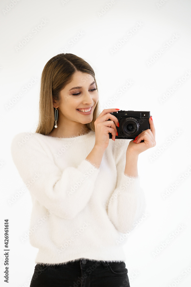 Beautiful Hipster woman taking photos with black retro film camera on white background. Close up. Indoor. Warm color. Blogger Beautiful Hipster woman taking photos with black retro film camera on white background. Close up. Indoor. Warm color. Blogger