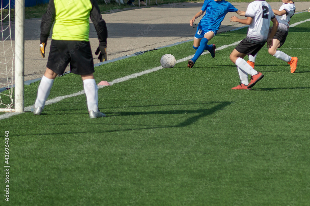 Fototapeta premium Children's football. Children are playing football. The active struggle and dynamics of the boys' soccer match. The boys are recklessly fighting for the ball