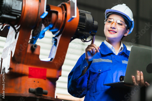 Fotografie engineer specialist asian female and  technician maintenance inspect relay robot arm system with laptop  to control quality operate process work heavy industry 4