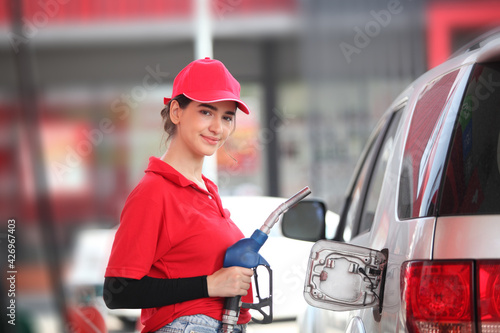 Photography woman with red uniform at the gas station for service , young woman refuel the