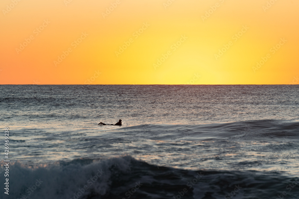 Silhouette of Surfer on the Ocean Waiting for the Sunrise. Narrabeen, Sydney, Australia.