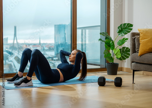 Foto Sportive brunette woman does crunches on glazed balcony