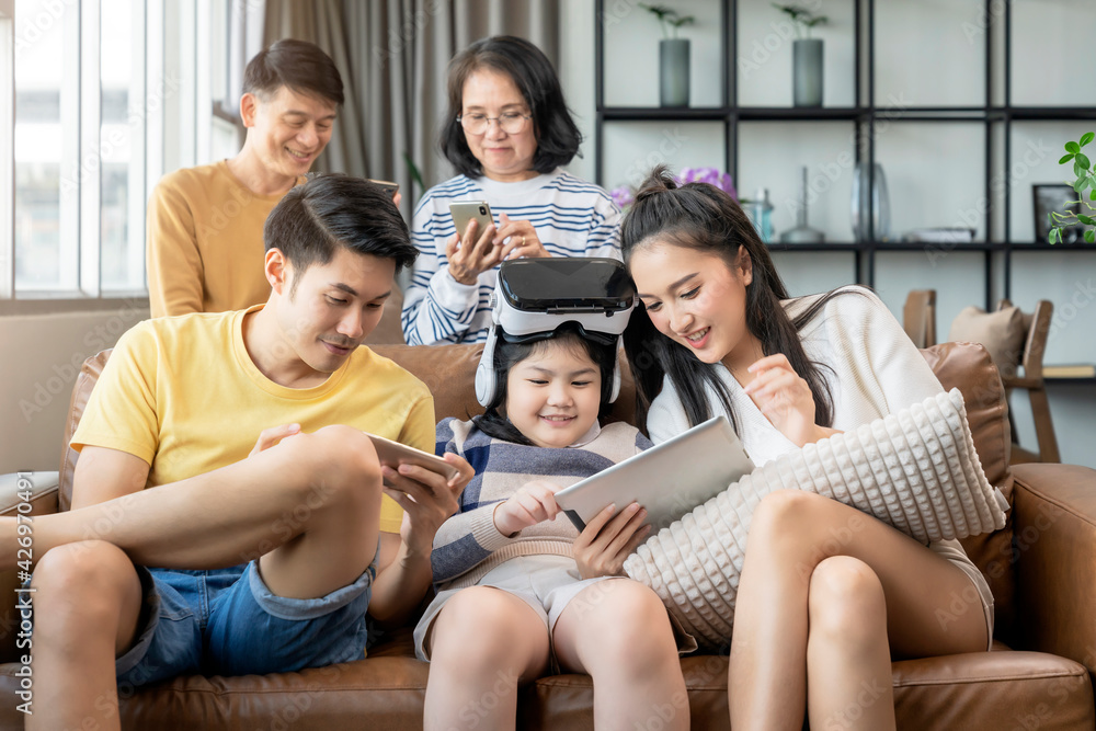 smart technology with lifestyle at home,asian generation family enjoy technology device hand use smartphone tablet and vr goggle glasses play fun together on sofa living room at home quarantine moment smart technology with lifestyle at home,asian generation family enjoy technology device hand use smartphone tablet and vr goggle glasses play fun together on sofa living room at home quarantine moment