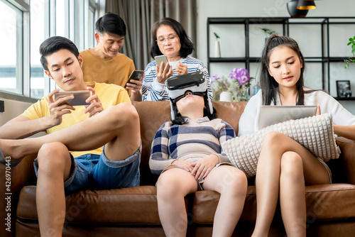 smart technology with lifestyle at home,asian generation family enjoy technology device hand use smartphone tablet and vr goggle glasses play fun together on sofa living room at home quarantine moment