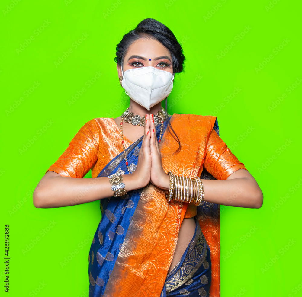 Indian woman wearing white mask gesturing Namaste, Mask is mandatory due to corona pandemic