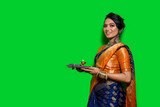 Traditional Beautiful Indian young girl holding pooja thali or performing worship on a green background