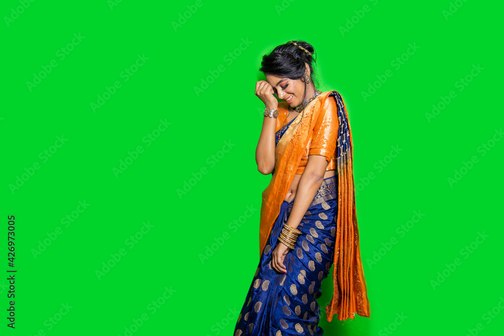 Indian traditional beautiful woman in traditional Marathi saree feeling shy, smiling, green background
