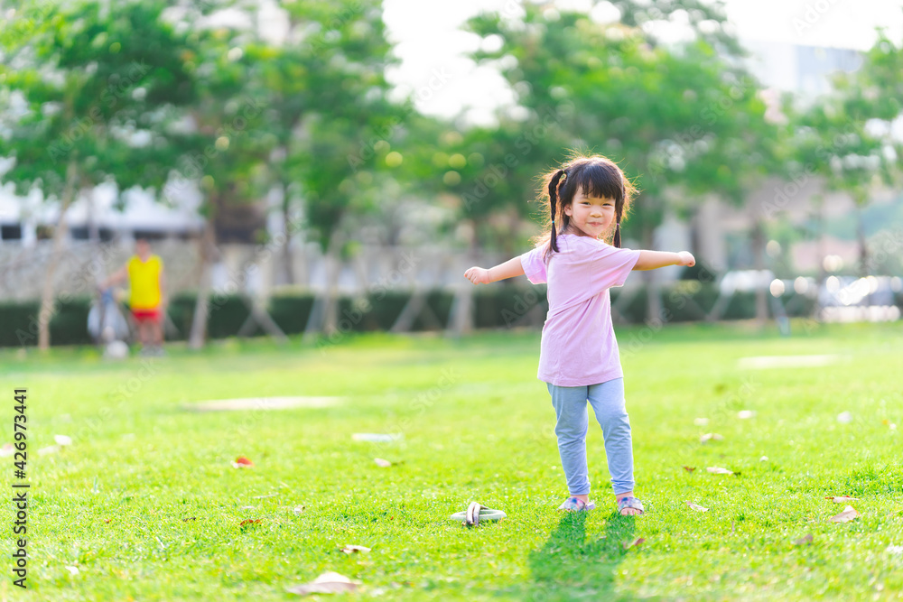 Cute Asian girl is exercising. Child standing and spread arms twist around. Kid smiled sweetly and laughed happily. On the green lawn. Warm sunshine in summer or spring. Children is 4 years old. Cute Asian girl is exercising. Child standing and spread arms twist around. Kid smiled sweetly and laughed happily. On the green lawn. Warm sunshine in summer or spring. Children is 4 years old.