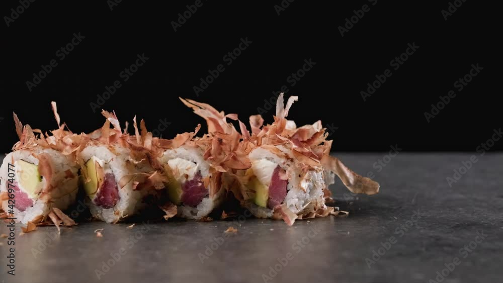 Sushi rolls with eel shavings at black background. Close-up shot with sliding camera and copy space. Delecious food with dried eel. Traditional asian food. 4K, UHD Sushi rolls with eel shavings at black background. Close-up shot with sliding camera and copy space. Delecious food with dried eel. Traditional asian food. 4K, UHD