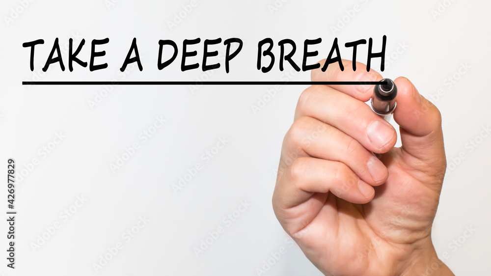 the hand writes text TAKE A DEEP BREATH with a marker on a white background. business concept the hand writes text TAKE A DEEP BREATH with a marker on a white background. business concept