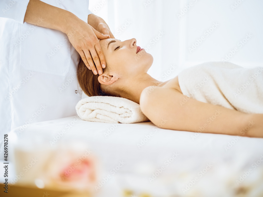 Beautiful woman enjoying facial massage with closed eyes in spa center