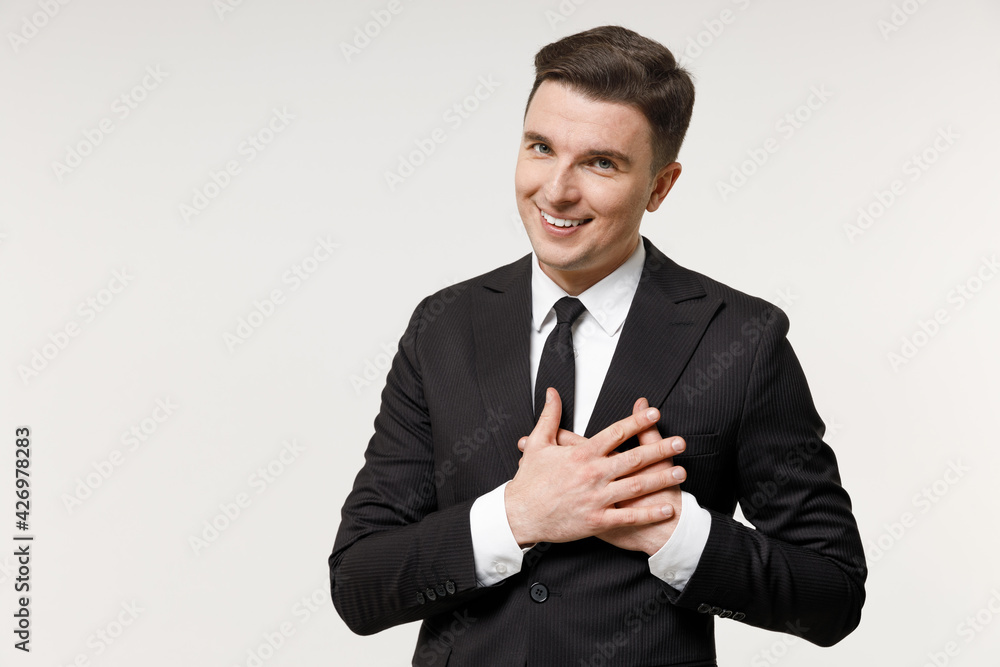 Young kind-hearted thankful employee business corporate lawyer man in classic formal black grey suit shirt tie work in office put folded hands on heart isolated on white background studio portrait Young kind-hearted thankful employee business corporate lawyer man in classic formal black grey suit shirt tie work in office put folded hands on heart isolated on white background studio portrait