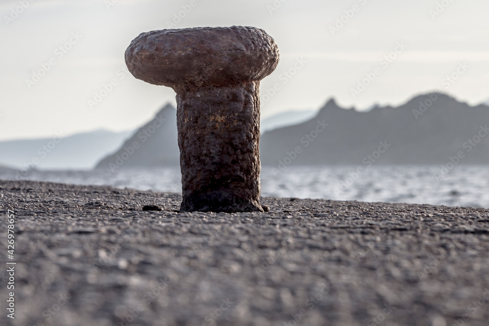 Profile of a rusted bollard left alone in the Aegean coast of Turkey, Turgutreis with Greek islands in the background and vanilla sky. Profile of a rusted bollard left alone in the Aegean coast of Turkey, Turgutreis with Greek islands in the background and vanilla sky.