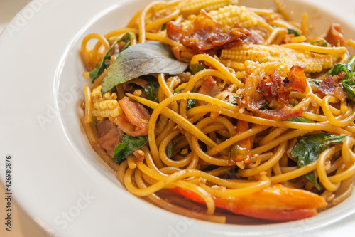 Spicy spaghetti with bacon and basil in the white dish. 