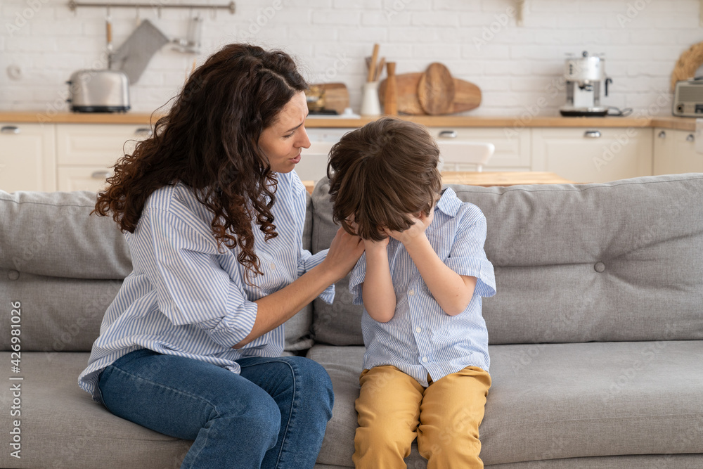 Stockfoto Closeup of worried mother calm weeping kid. Upset little boy cry  sit on couch together with caring mom. Young parent support depressed child  in difficult times. Woman comforting offended by mates