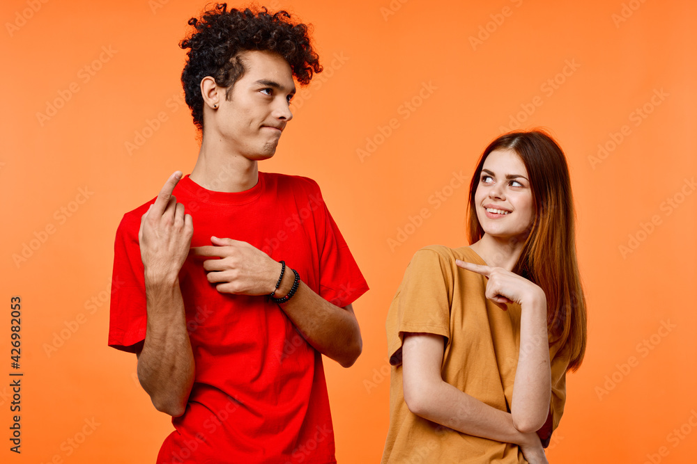 guy and girl in colorful t-shirts fun studio orange background guy and girl in colorful t-shirts fun studio orange background