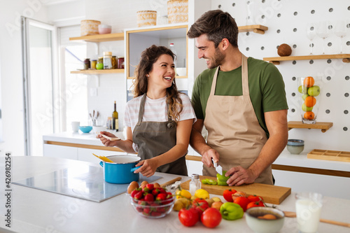 Young happy couple is enjoying and preparing healthy meal in their kitchen