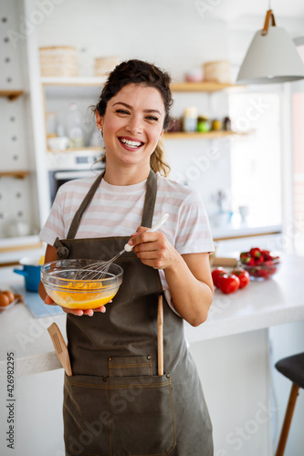 Happy woman making healthy food standing smiling in kitchen preparing food