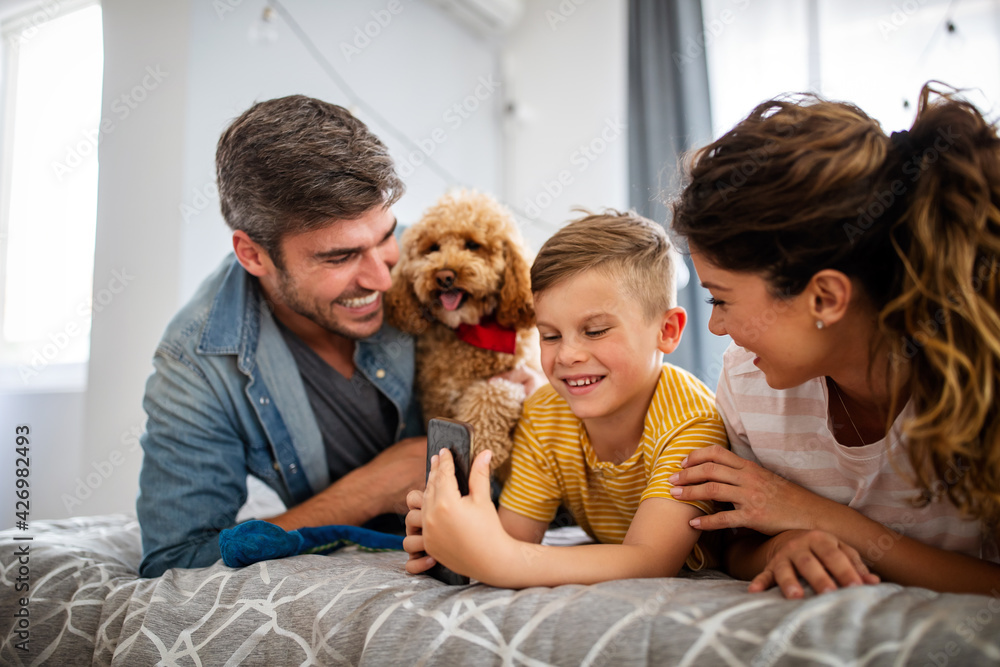 Happy young friendly family spending fun times together and cuddling with their pet at home